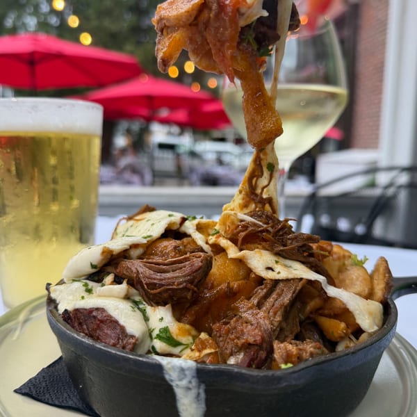 Under the Moon's poutine with pulled pork, cheese curds, and gravy, with beer and wine on an outdoor patio.
