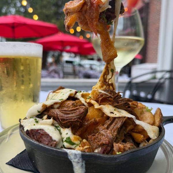 Under the Moon's New American poutine with braised short rib, cheese curds, and gravy, with drinks outdoors.